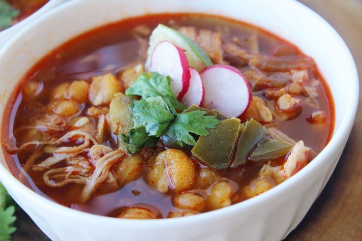 a white bowl filled with soup and garnished with radishes