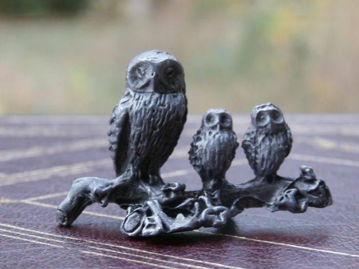 three little owls sitting on a tree branch figurine, one is black and the other is gray