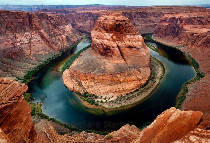 an aerial view of a river in the middle of a canyon with cliffs surrounding it