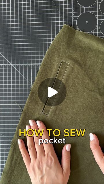 someone is using their hands to sew the pocket on a green piece of cloth