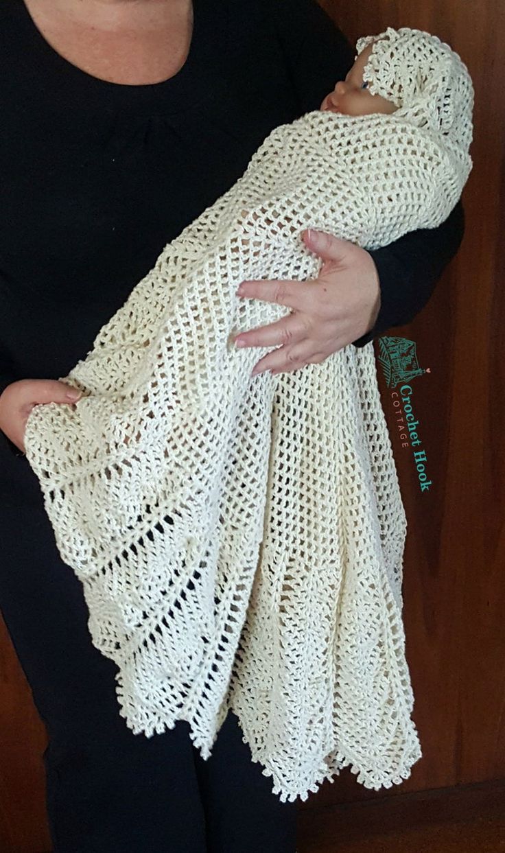 a woman holding a white crocheted shawl in front of a wooden door