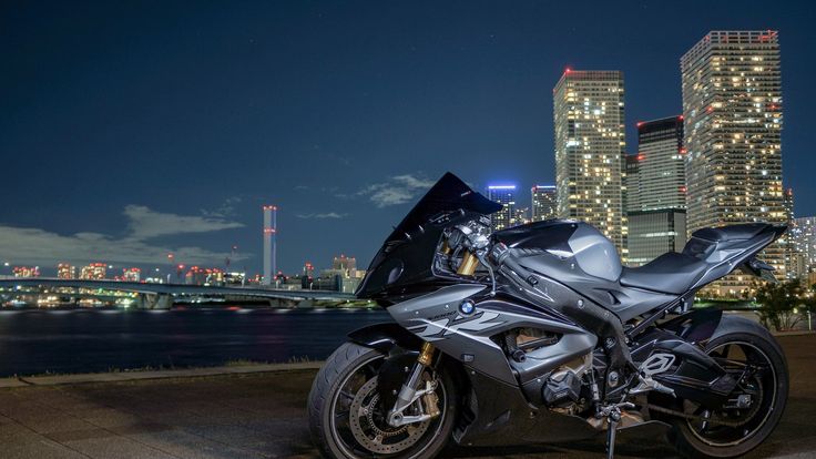 a silver motorcycle parked in front of a city at night