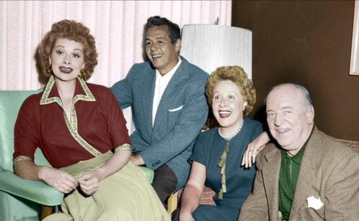 an old black and white photo of three people sitting on a couch with a lamp in the background