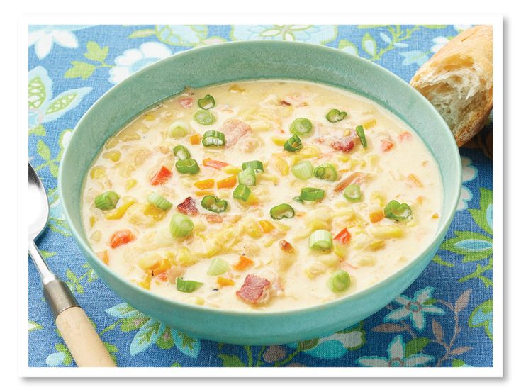 a blue bowl filled with soup next to a piece of bread on top of a table