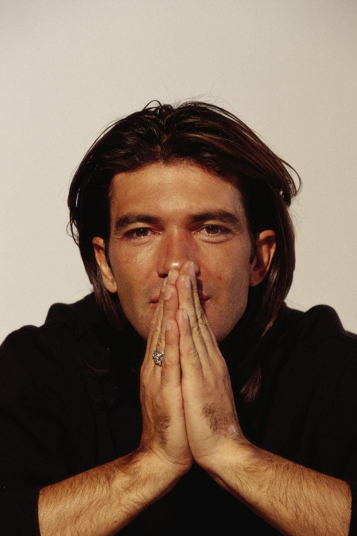 a man with his hands folded in front of his face and eyes wide open, making a praying gesture