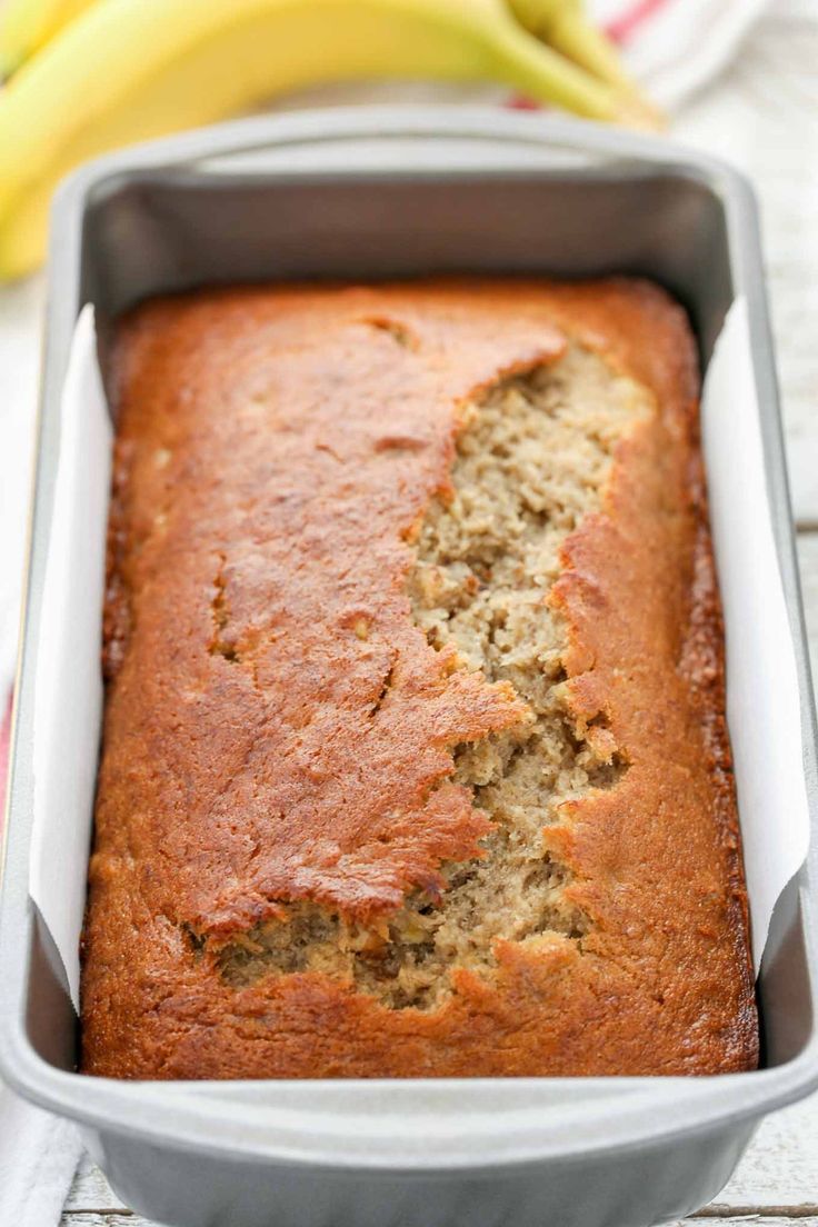 a loaf of banana bread sitting in a pan on top of a table next to bananas