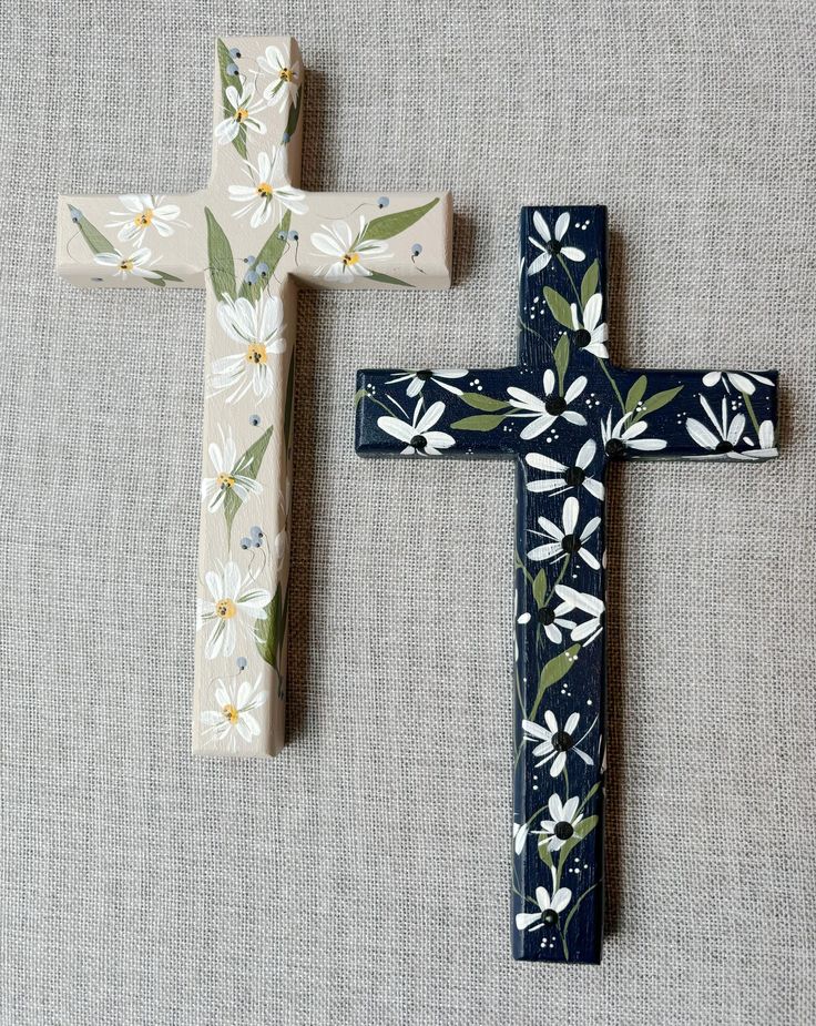 two wooden crosses with flowers painted on them sitting next to each other in front of a gray background