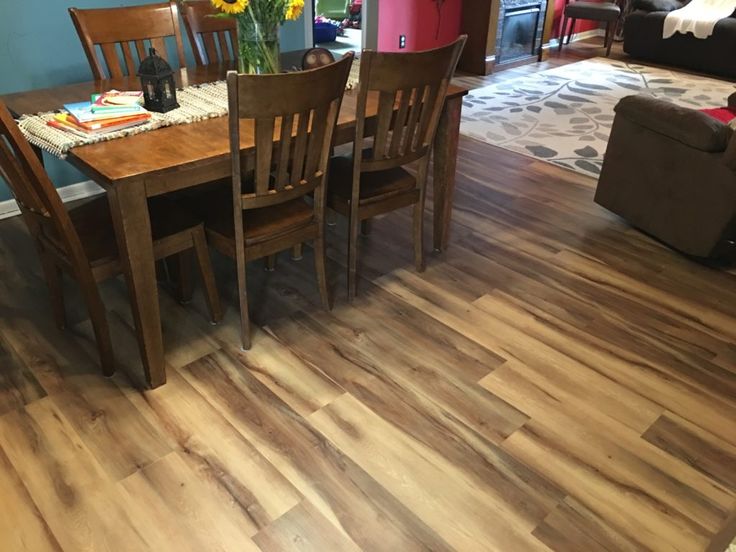 a dining room table with chairs and flowers on the wooden floor in front of it