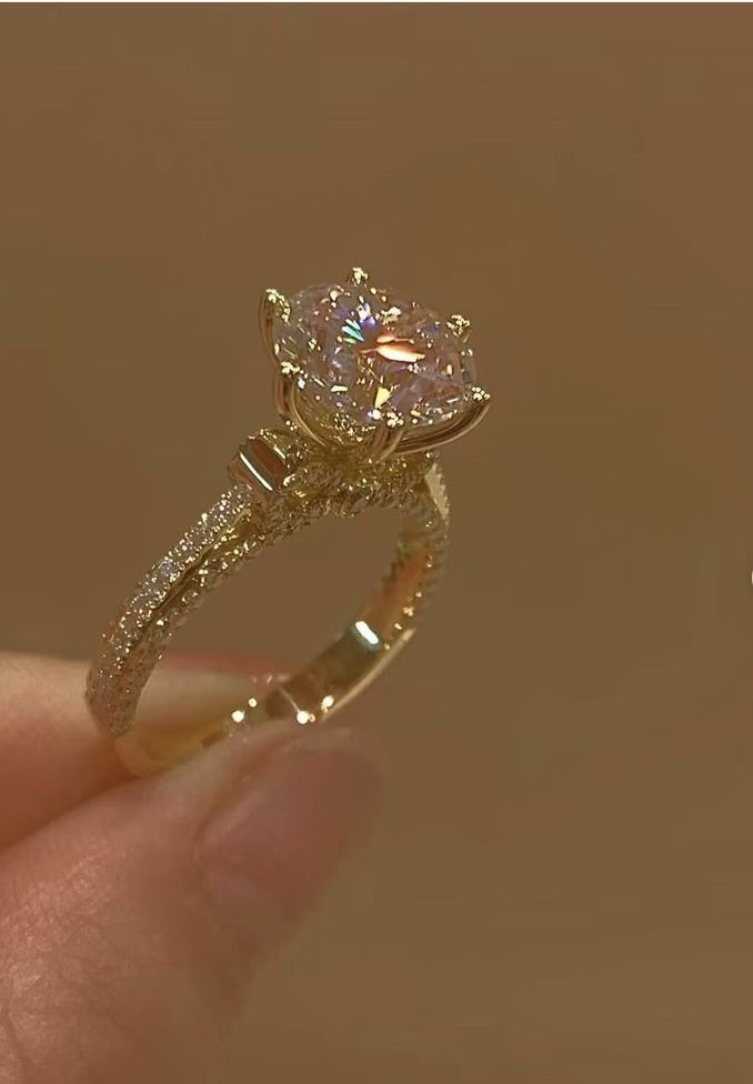 a close up of a person's hand holding a ring with a diamond on it