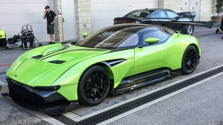 a lime green sports car parked in front of a garage with two men looking at it