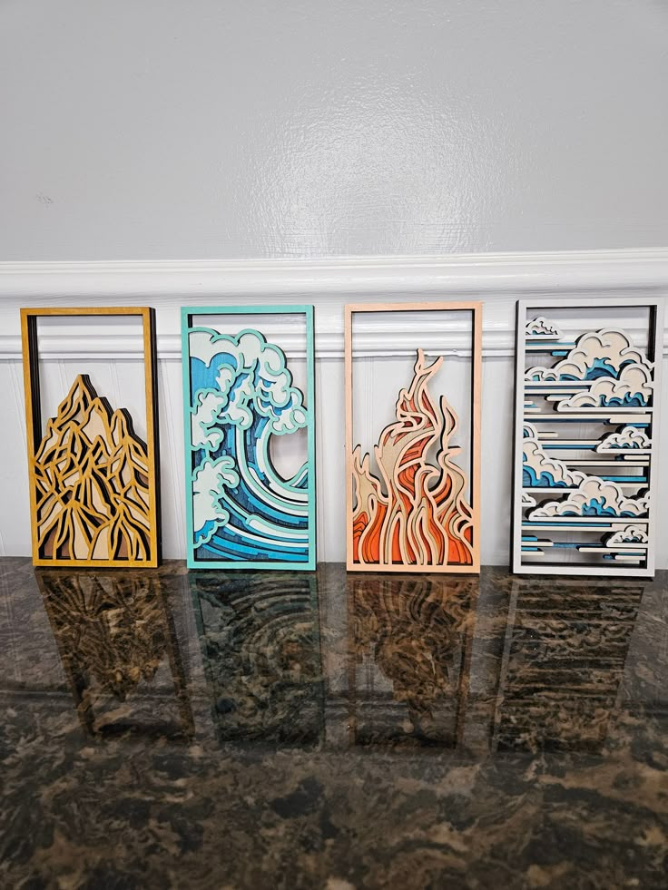 four different colored paper art pieces sitting on top of a marble counter next to a white wall