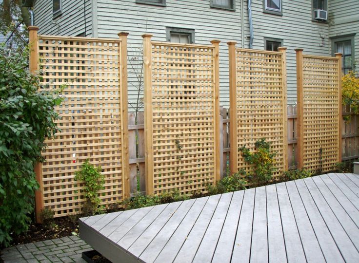 a wooden fence next to a building with plants growing on the side and in front