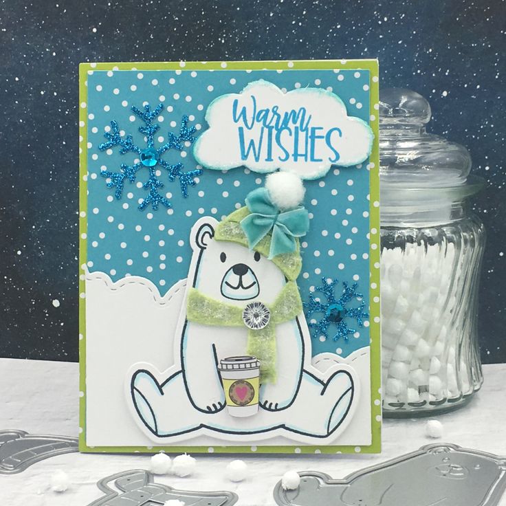 a card with a bear and snowflakes on the table next to it is a cookie tin