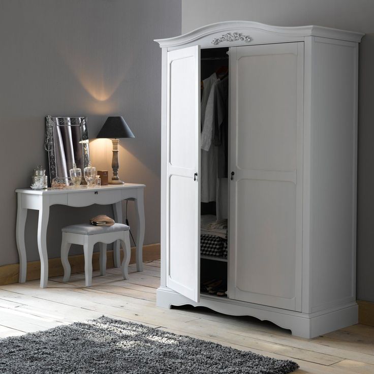 a white armoire sitting next to a desk and chair in a room with gray walls