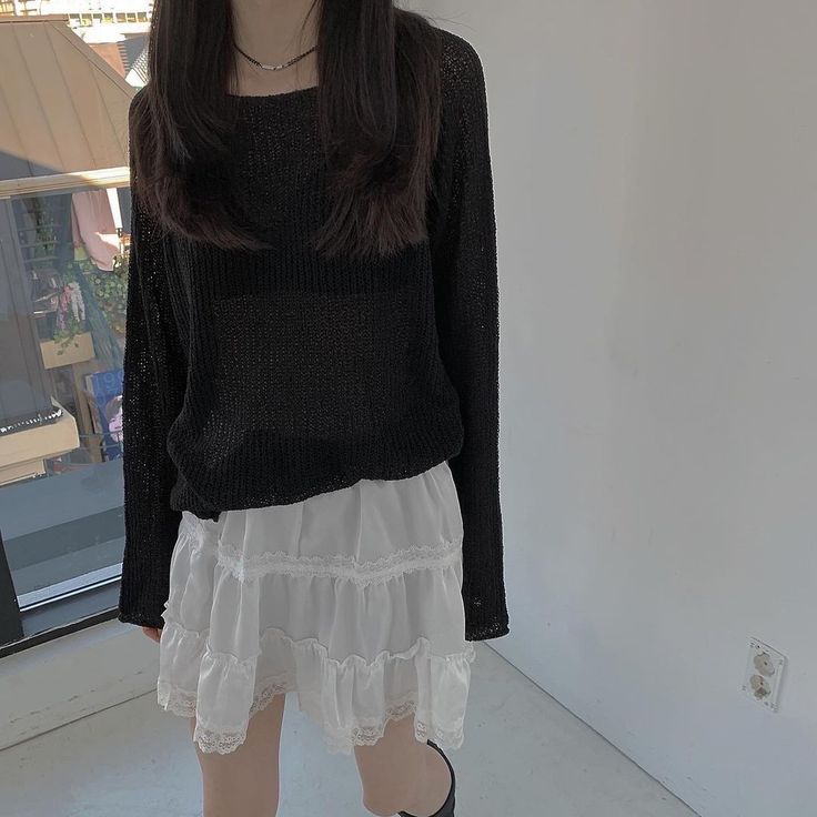 a woman standing in front of a window wearing black boots and a white frilly skirt