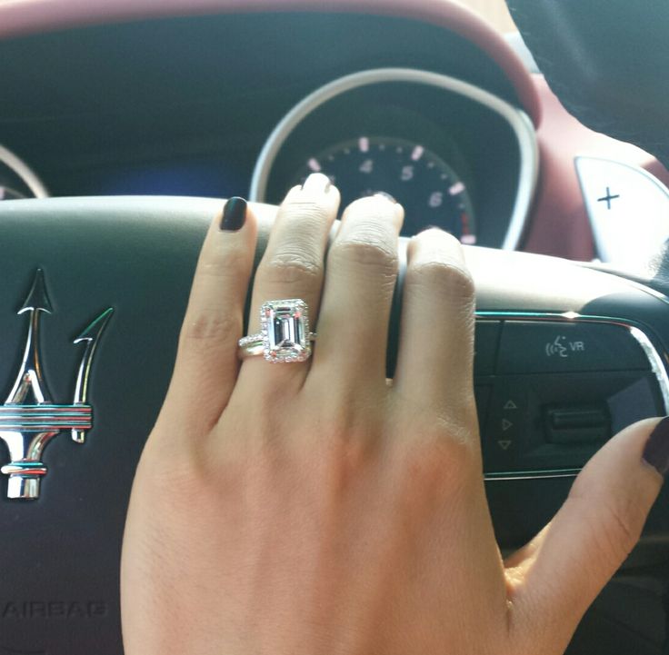 a woman's hand on the steering wheel of a car with an emerald ring