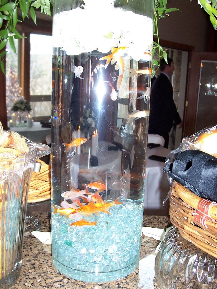 a vase filled with water and goldfish in it on top of a table next to other items