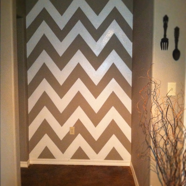 a bathroom decorated with gray and white chevrons on the wall, along with utensils