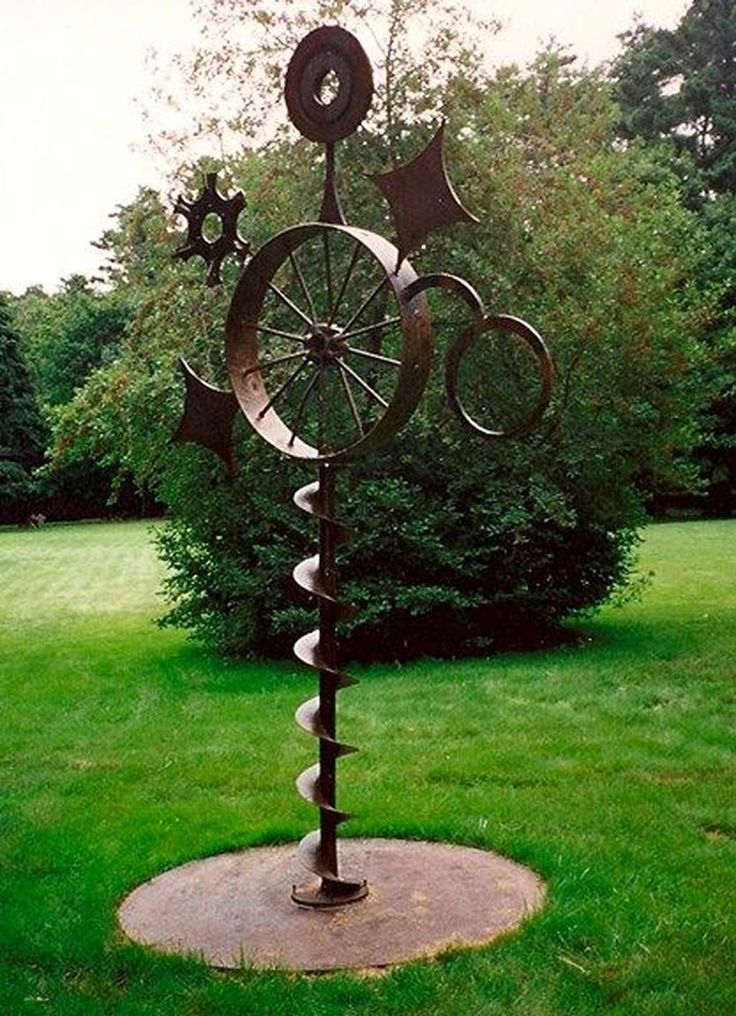 a metal sculpture in the middle of a grassy field