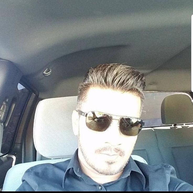 a man wearing sunglasses sitting in the back seat of a car with his head turned to the side