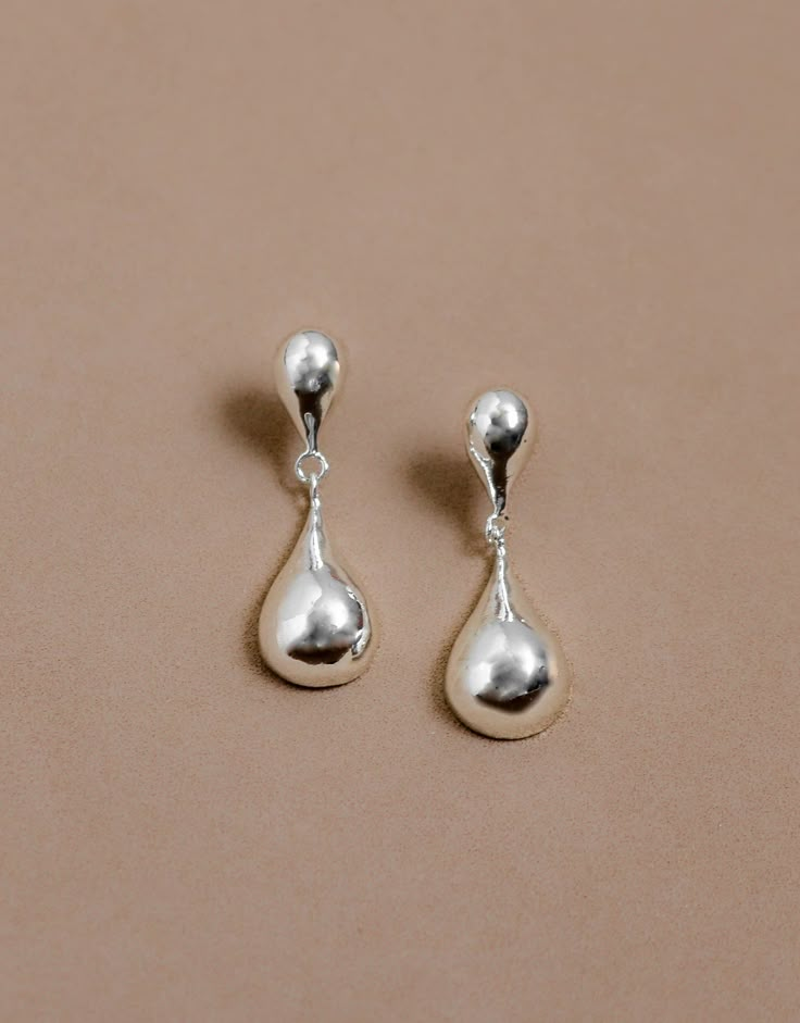 Color | Silver Made in Colombia Our Rain Drops earrings are the perfect blend of classic shapes and modern styling. They are hand-carved in bronze with a 925 Sterling Silver coating. They feature a drop-shaped earring design that moves slightly as you walk. Wear them with a solid-colored shirt for a stunning look. MEDIDAS 1.5 inches height x 0.43 inches width CUIDADOS Avoid contact with any liquid or moist substance. Store your piece in a cool place and always clean it with a dry cloth after wea Cheap Glass Dangle Earrings, Silver Pendant Earrings, Silver Vintage Earrings, Silver Teardrop Earrings, Dangly Silver Earrings, Cute Silver Earrings, Vocal Point, Rain Jewelry, Simple Silver Earrings