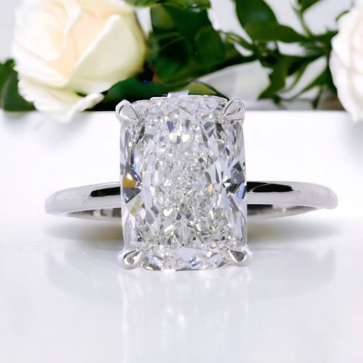 a close up of a diamond ring with flowers in the background