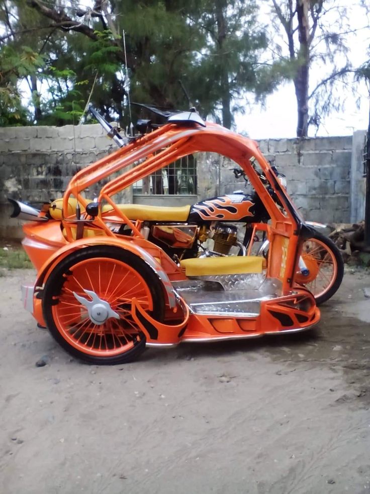 an orange motorcycle parked on top of a dirt road