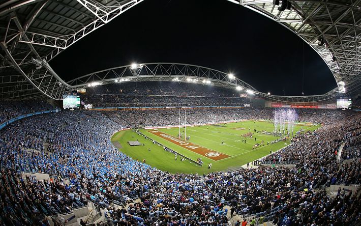 a stadium filled with lots of people watching a football game on the field at night