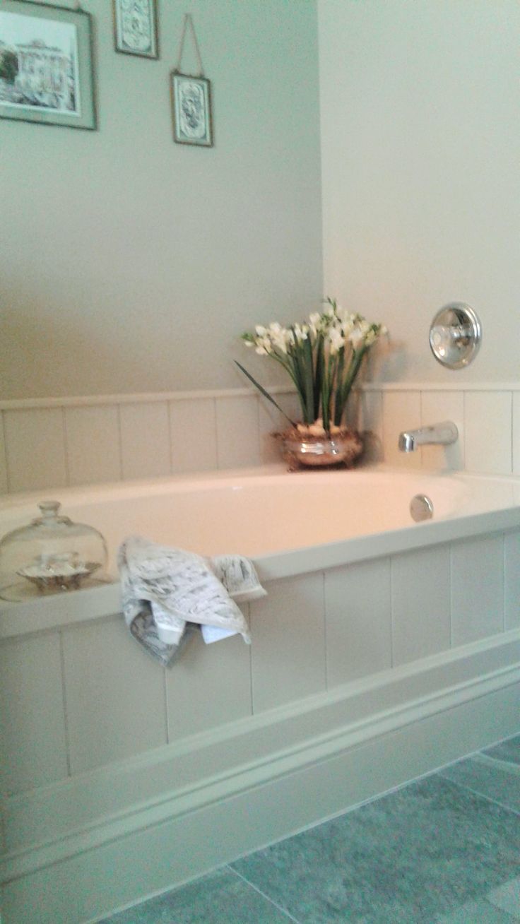 a white bath tub sitting next to a window with pictures on the wall above it