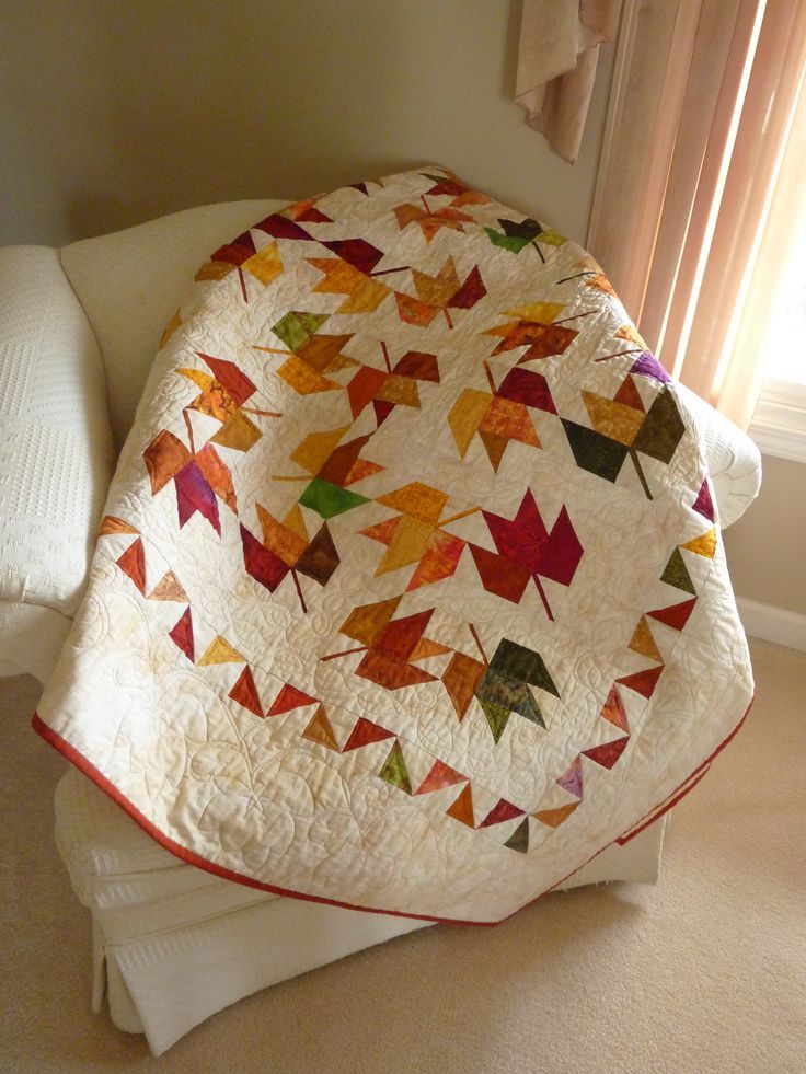 a bed with a quilt on top of it next to a pillow and window sill