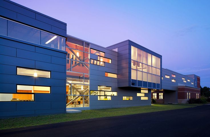 an office building lit up at night with lights on the windows and grass in front