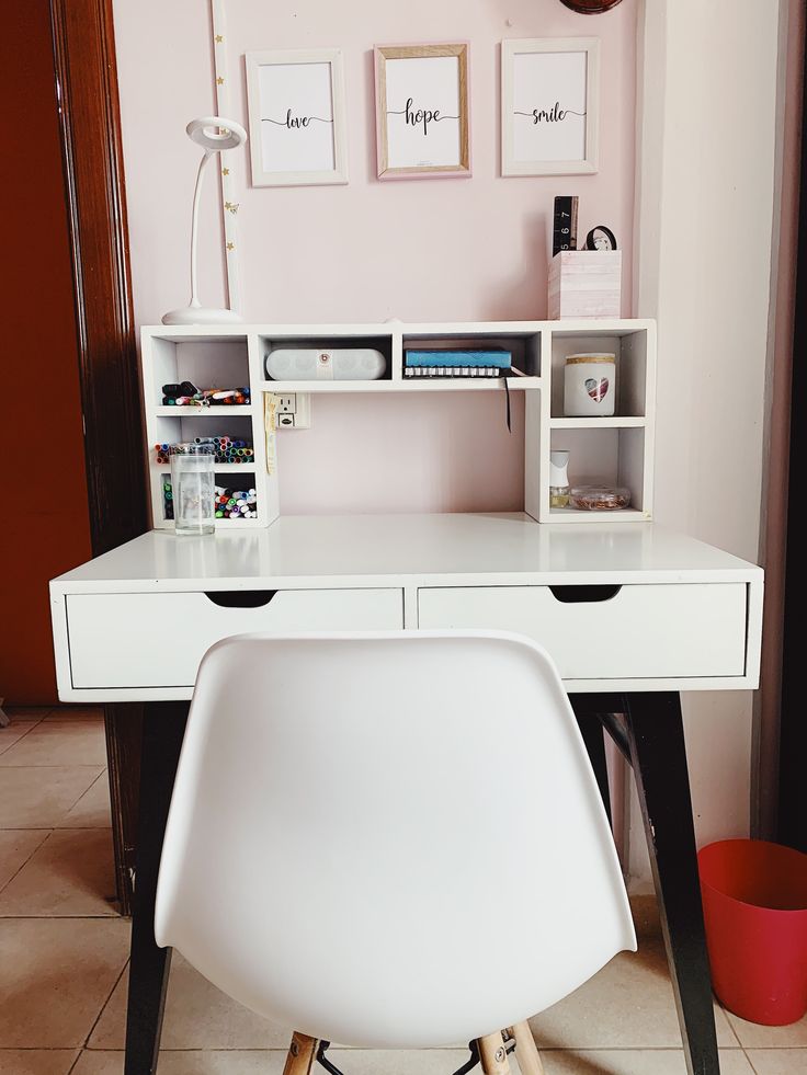 a white desk and chair in a room with pictures on the wall above it,