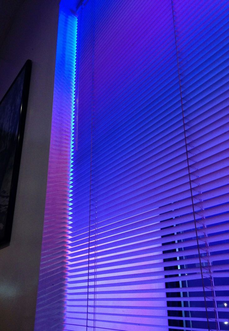 purple and blue light shining through blinds in a room