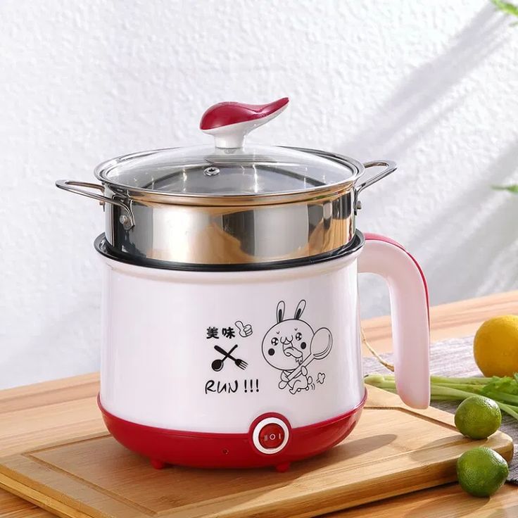 an electric rice cooker sitting on top of a cutting board next to some vegetables