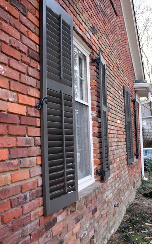 a red brick house with shutters open