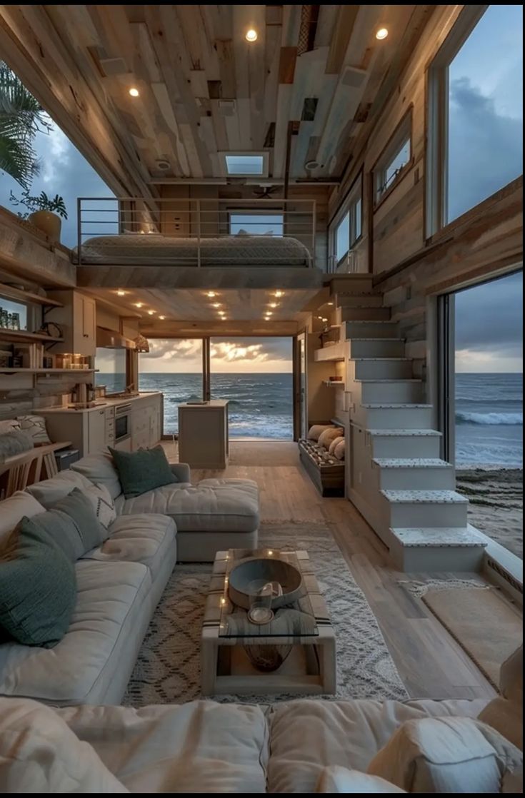 a living room with couches and stairs leading to the ocean