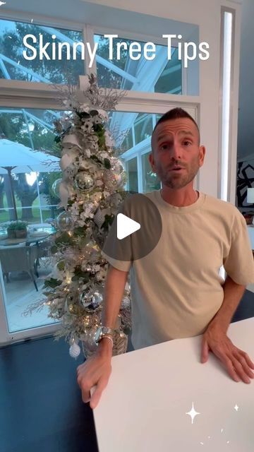 a man standing next to a white table with a christmas tree on top of it