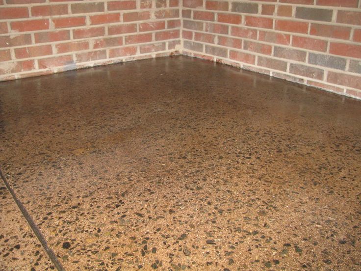 the floor is covered in brown and black speckles, with a brick wall behind it