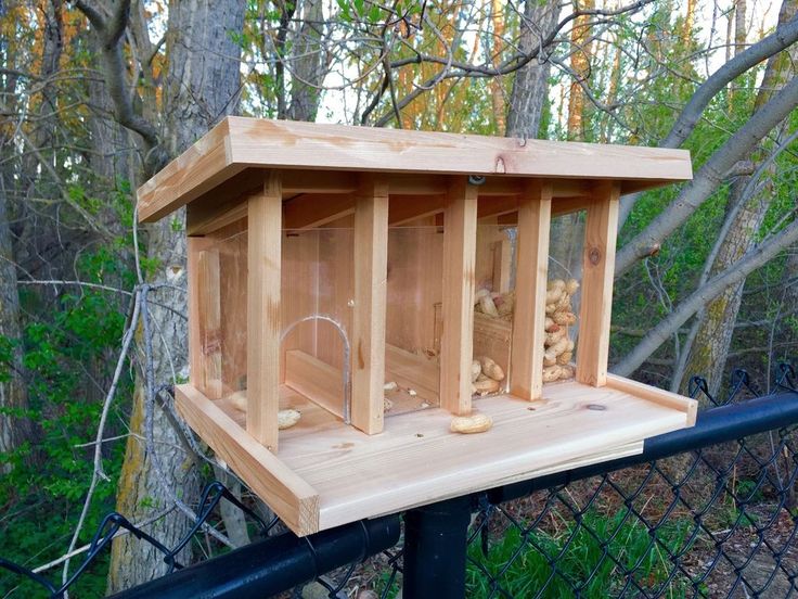 a wooden bird feeder on top of a fence