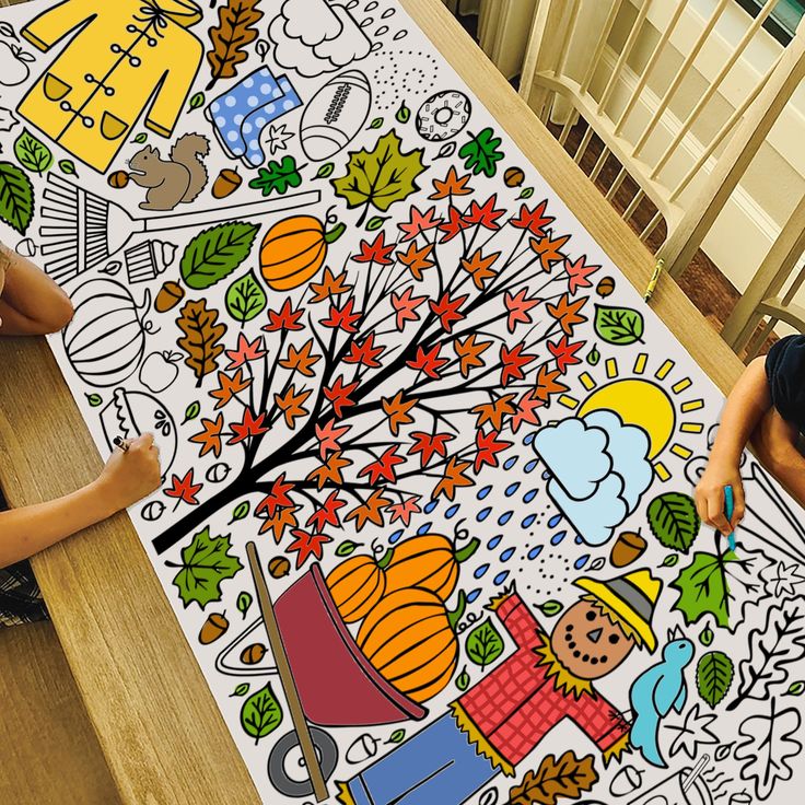 two children sitting at a table in front of a large coloring book on the floor