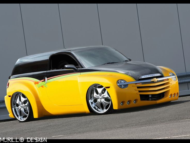 a yellow and black car parked on the side of a road next to a building