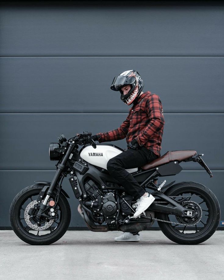 a man sitting on top of a motorcycle in front of a garage door wearing a helmet