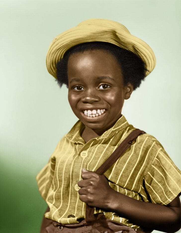 a young boy wearing a hat and holding a brown bag