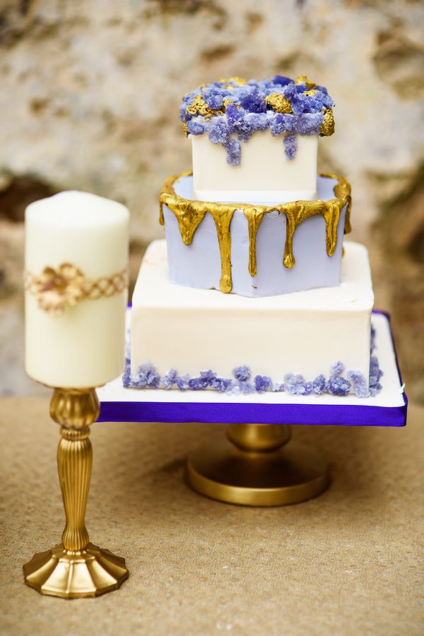 a three tiered cake with blue flowers on it and a candle next to it