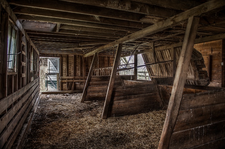 an old barn with hay in the floor and wooden structures on the walls, along with windows