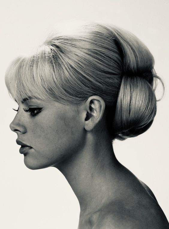 a black and white photo of a woman with her hair in a high bun hairstyle