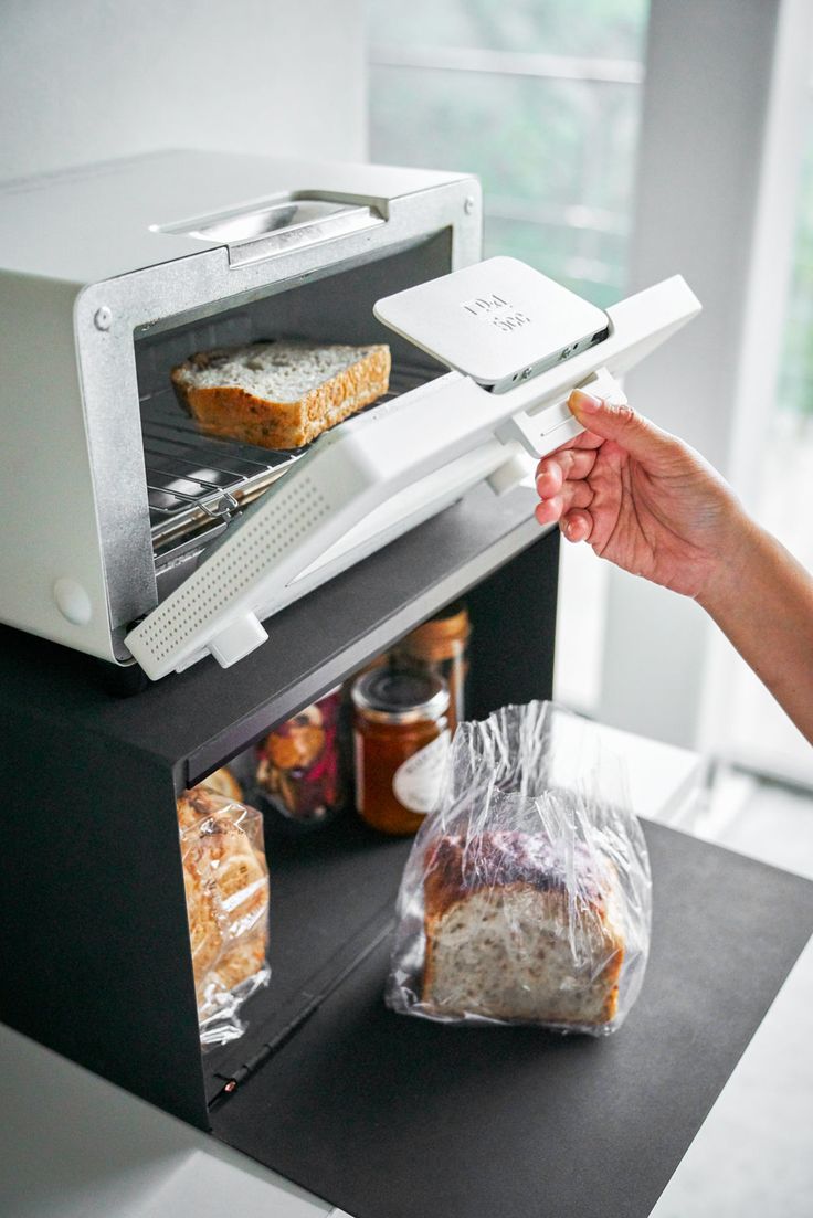 a toaster oven with bread in it being held up by someone's hand