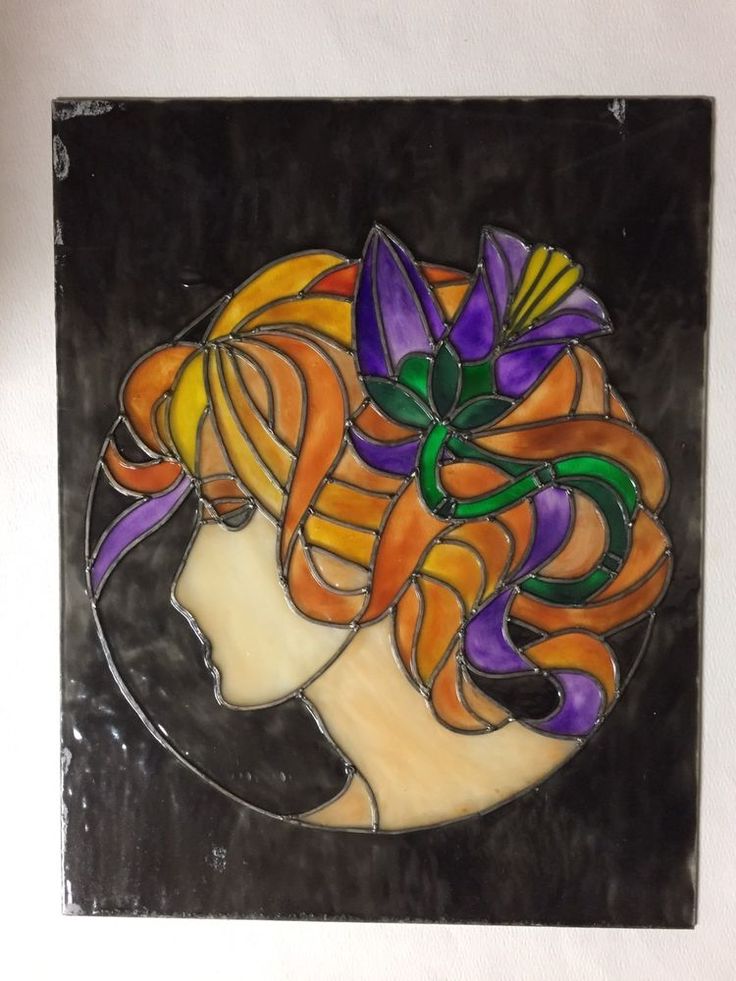 a stained glass artwork depicting a woman's head with flowers in her hair on a black background