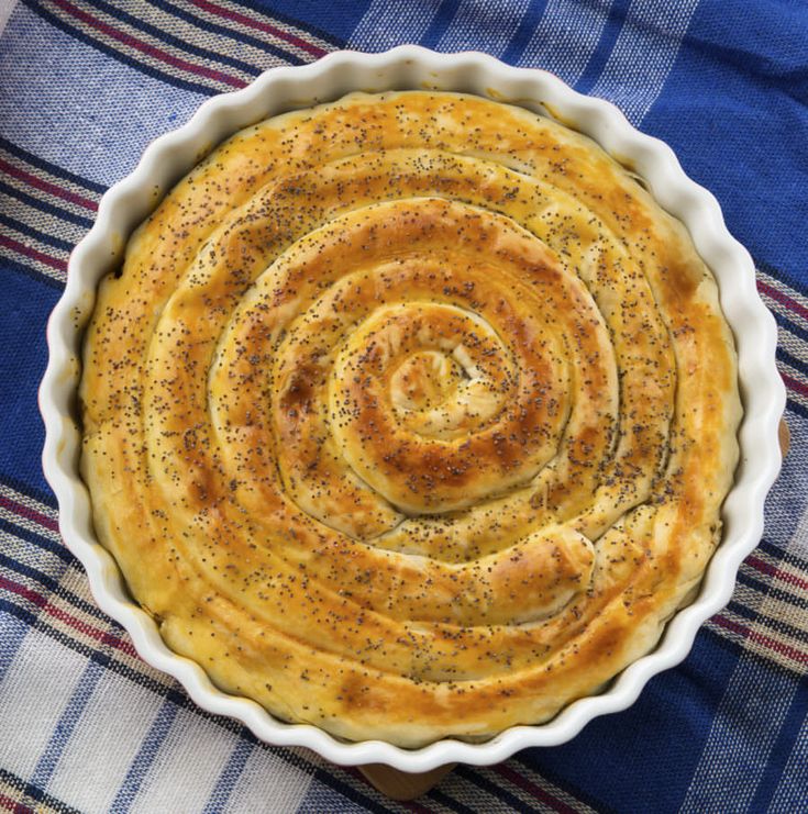 a pie crust in a white dish on top of a blue towel