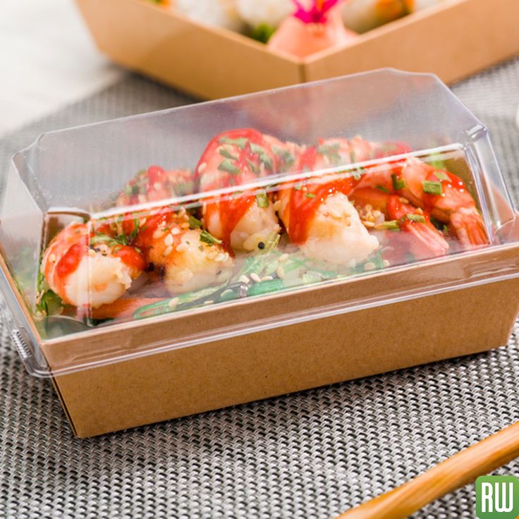 some food is in a plastic container on a table with chopsticks and rice